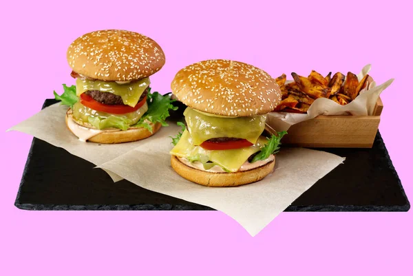 İki büyük burger ve siyah taş tabakta izole edilmiş tatlı patates. gül arkaplanı