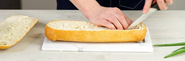 El cocinero corta el pan fresco de ciabatta. Saca la pulpa del interior. Hace una base para el relleno de pan. proceso de fabricación de sándwich enorme. — Foto de Stock
