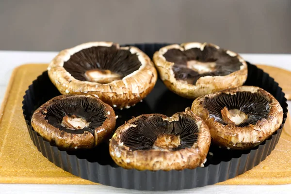 Şampiyon mantarları pişirme işlemi. Tabakta çiğ Portobello var. Doldurulmuş portobello mantarı pişirme işlemi. Vejetaryen yemeği.