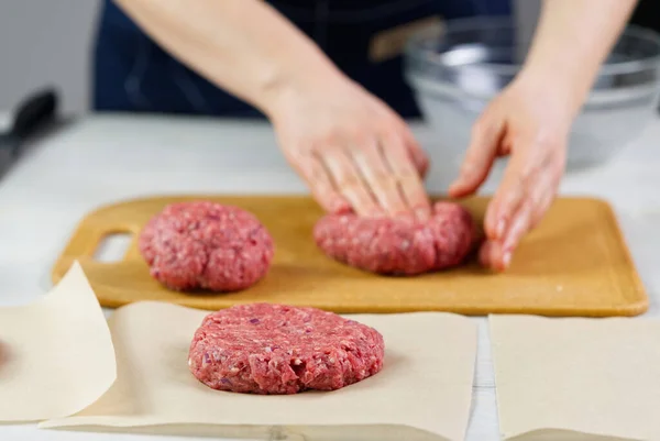 Hamburger partisi için et yapan kadın eli. Kıyma porsiyonu. Ev yapımı hamburgerler. Evde yemek yapmak..