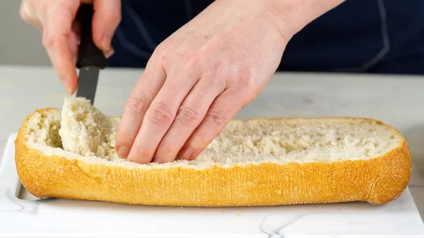 Aşçı taze ciabatta ekmeği keser. Postayı içeriden çıkartıyor. Ekmek doldurmak için bir zemin hazırlıyor. büyük sandviç yapma süreci.