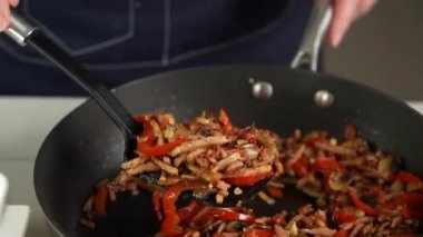 Şef, jambon, paprika ve mantarı seramik bir yemek kabına koyar.