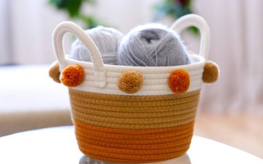 Hasır sepetin üst görüntüsü, el örgü için yün yumakları, eski ahşap bir masa üzerinde kancalar ve örgü iğneleri..