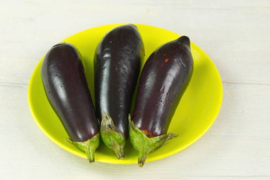 Işık masasında 3 patlıcan. Yeşil bitkideki taze Mor Patlıcan.