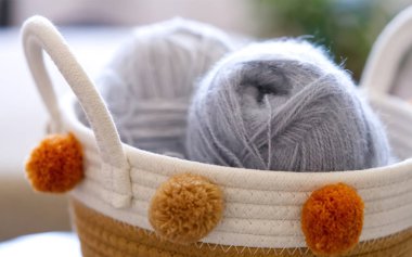 Hasır sepetin üst görüntüsü, el örgü için yün yumakları, eski ahşap bir masa üzerinde kancalar ve örgü iğneleri..