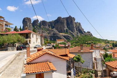 Kalabaka kasabasının uçurumun tepesindeki manzarası çok güzel. Kırmızı çatılı küçük evler. Yunanca. Kapat.