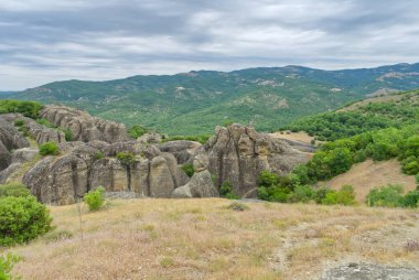 Yunanistan. Meteora dağ vadisinde güneşli bir yaz akşamı. Uçurumun tepesindeki taş manastır. Kapat.
