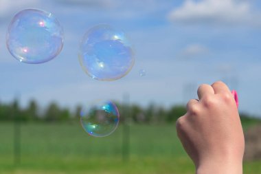 Çocuk doğada sabun köpüğü üflüyor. Kapat.