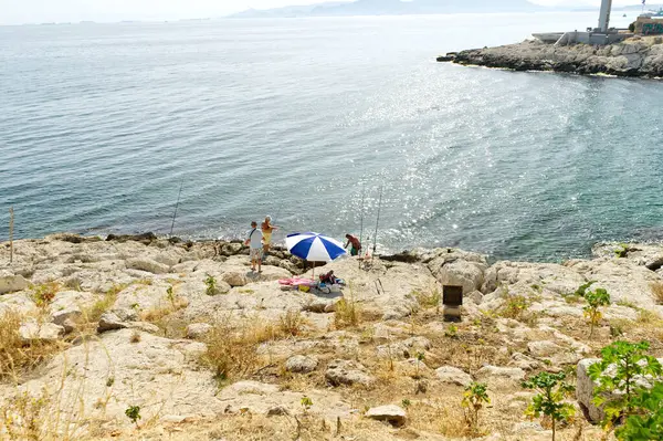 Tourists Enjoy Fishing Clear Blue Water Sea Standing Rocky Beach — Stok fotoğraf