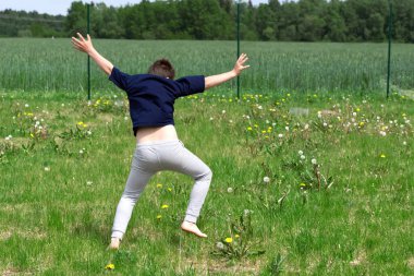 Çocuk akrobatik tekerlek yapıyor. Çimlerin üzerinde. Kapat.