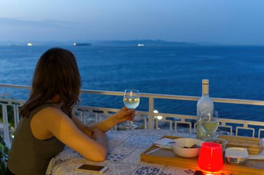 young girl on the balcony with a romantic table by candlelight and a sea view. close up