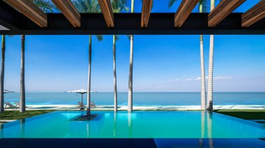 Park yeri ve havuzu olan ya da deniz ya da okyanus kıyısında ahşap cepheli modern konforlu bir ev. Tropikal adada palmiye ağaçları ve çiçeklerle masmavi sahilde güneşli bir gün.