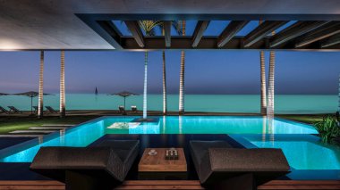 Park yeri ve havuzu olan ya da deniz ya da okyanus kıyısında ahşap cepheli modern konforlu bir ev. Tropikal adada palmiye ağaçları ve çiçeklerle masmavi sahilde yıldız ışığı gecesi