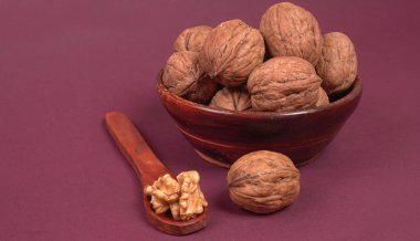 Eflatun arka planda tahta kaşıkla ceviz yığını 