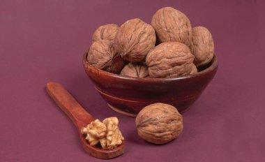 Eflatun arka planda tahta kaşıkla ceviz yığını 