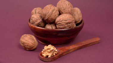 Eflatun arka planda tahta kaşıkla ceviz yığını 