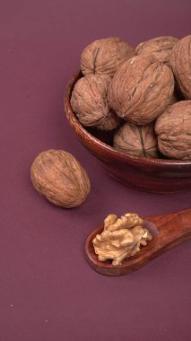 Eflatun arka planda tahta kaşıkla ceviz yığını 