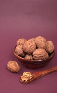 Eflatun arka planda tahta kaşıkla ceviz yığını 