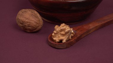 Eflatun arka planda tahta kaşıkla ceviz yığını 