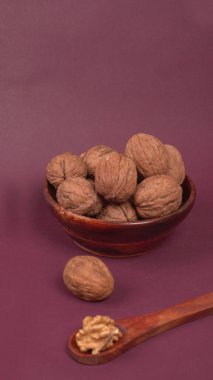 Eflatun arka planda tahta kaşıkla ceviz yığını 