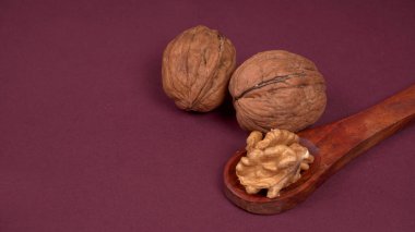 Eflatun arka planda tahta kaşıkla ceviz yığını 