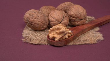 Eflatun arka planda tahta kaşıkla ceviz yığını 