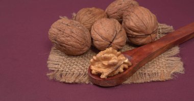 Eflatun arka planda tahta kaşıkla ceviz yığını 