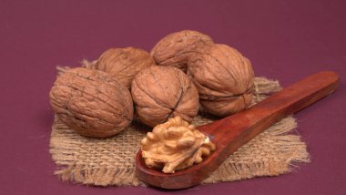 Eflatun arka planda tahta kaşıkla ceviz yığını 