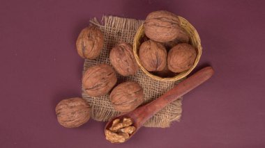 Eflatun arka planda tahta kaşıkla ceviz yığını 