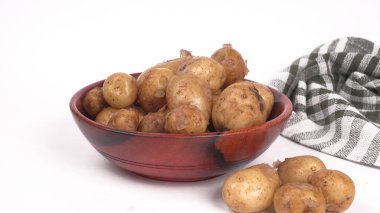 Beyaz arka planda ahşap kasede pişirmek için taze patatesler. 