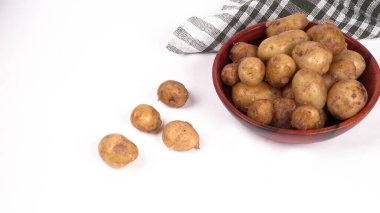 Beyaz arka planda ahşap kasede pişirmek için taze patatesler. 
