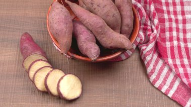 Tahta arka planda tatlı patates dilimleri, yakın plan. Çiğ patates ya da yarasa.