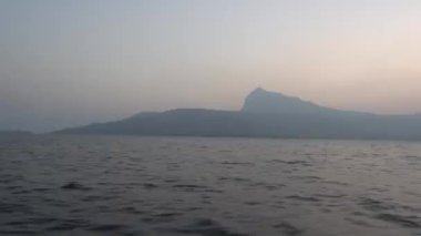 Denizdeki gemiden POV, küçük adanın üstünde günbatımı gökyüzü 