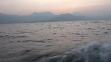 Denizdeki gemiden POV, küçük adanın üstünde günbatımı gökyüzü 