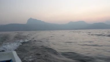 Denizdeki gemiden POV, küçük adanın üstünde günbatımı gökyüzü 