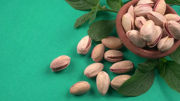 Pistachios Pista Nuts Decorated Green Leaves Brown Bowl Green Background — Stockfoto