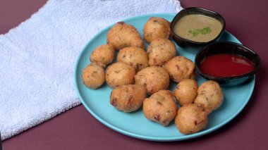 Lezzetli Hint atıştırmalıkları Punugulu, domates ve yeşil soslu bir tabakta servis ediliyor. 
