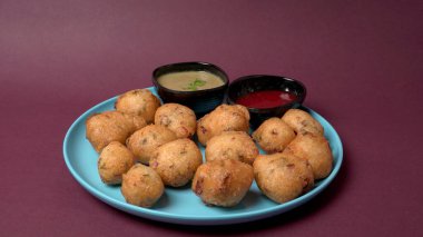 Lezzetli Hint atıştırmalıkları Punugulu, domates ve yeşil soslu bir tabakta servis ediliyor. 