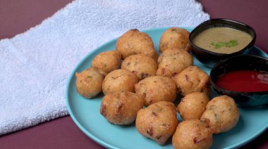 Lezzetli Hint atıştırmalıkları Punugulu, domates ve yeşil soslu bir tabakta servis ediliyor. 