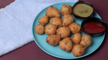 Lezzetli Hint atıştırmalıkları Punugulu, domates ve yeşil soslu bir tabakta servis ediliyor. 