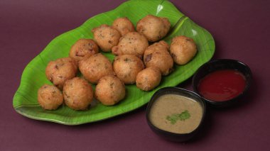 Lezzetli Hint atıştırmalıkları Punugulu, domates ve yeşil soslu bir tabakta servis ediliyor. 