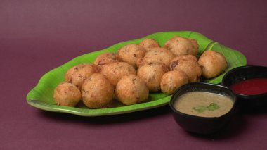 Lezzetli Hint atıştırmalıkları Punugulu, domates ve yeşil soslu bir tabakta servis ediliyor. 