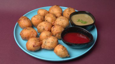 Lezzetli Hint atıştırmalıkları Punugulu, domates ve yeşil soslu bir tabakta servis ediliyor. 