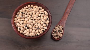 Ahşap kaşıklı bir kase pişmemiş siyah bezelye. Sağlıklı gıda kavramı.