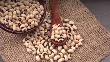 Ahşap kaşıklı bir kase pişmemiş siyah bezelye. Sağlıklı gıda kavramı.