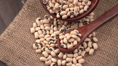 Ahşap kaşıklı bir kase pişmemiş siyah bezelye. Sağlıklı gıda kavramı.