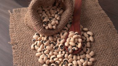 Ahşap kaşıklı pişmemiş siyah bezelyeler. Sağlıklı gıda kavramı.