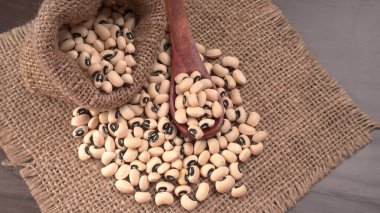 Ahşap kaşıklı pişmemiş siyah bezelyeler. Sağlıklı gıda kavramı.