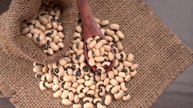 Ahşap kaşıklı pişmemiş siyah bezelyeler. Sağlıklı gıda kavramı.