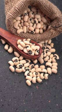 Ahşap kaşıklı pişmemiş siyah bezelyeler. Sağlıklı gıda kavramı.